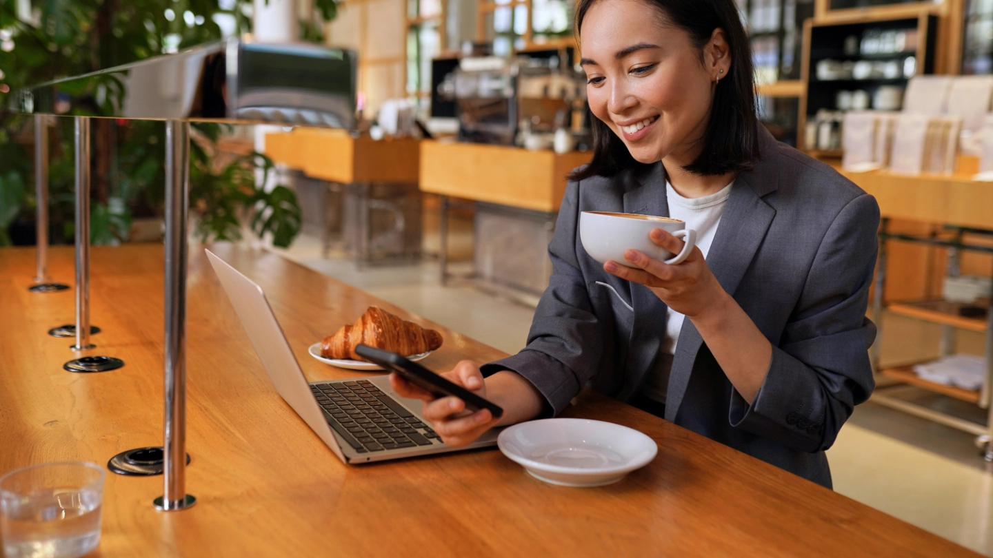 Young Asian business woman drinking coffee using smartphone in cafe Young Asian business woman drinking coffee using smartphone in cafe