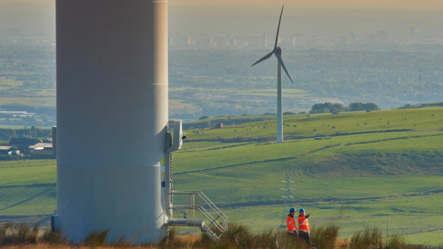 two construction workers in a field with windmills image